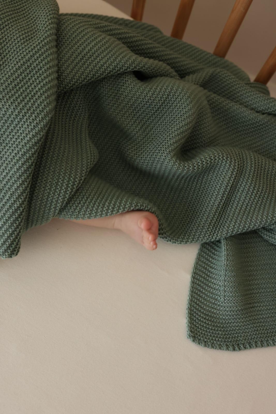 Little Dedi Alina blanket green in nursery decor beside plush toys.