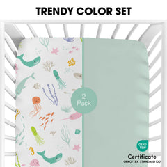Little Grape Land pastel ocean crib sheet folded beside baby toys, easy care and durable fabric.