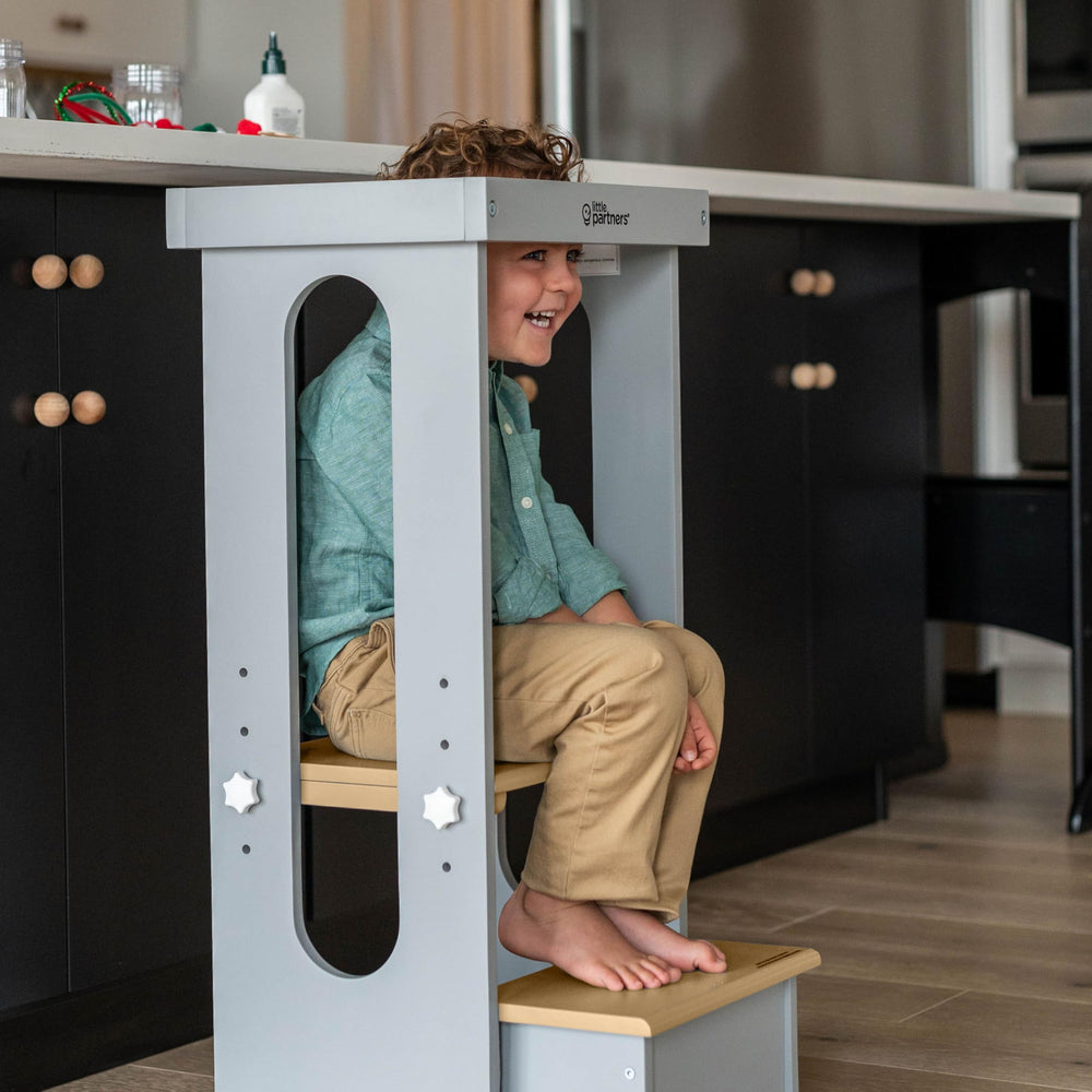 Child standing at the counter using the Little Partners Tower during a cooking activity.