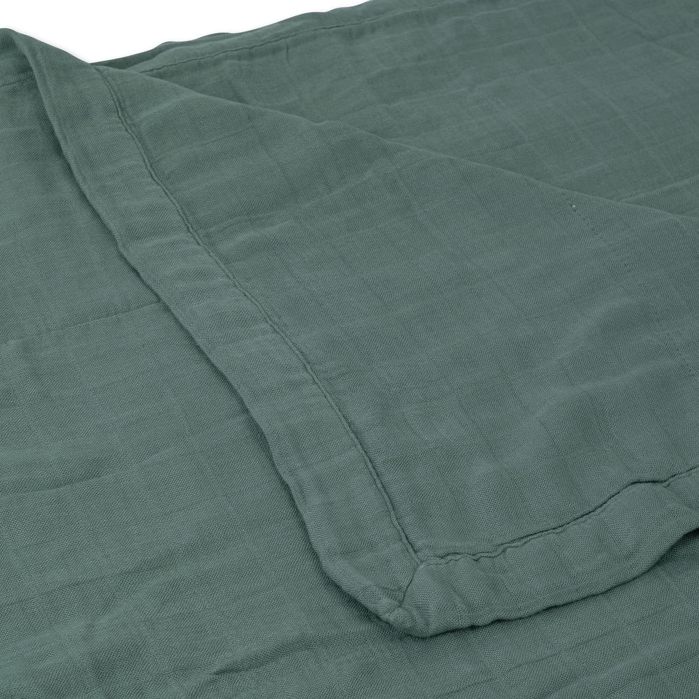 Little Unicorn Deluxe Muslin Quilt draped over toddler for versatile bedtime wrap and play mat.