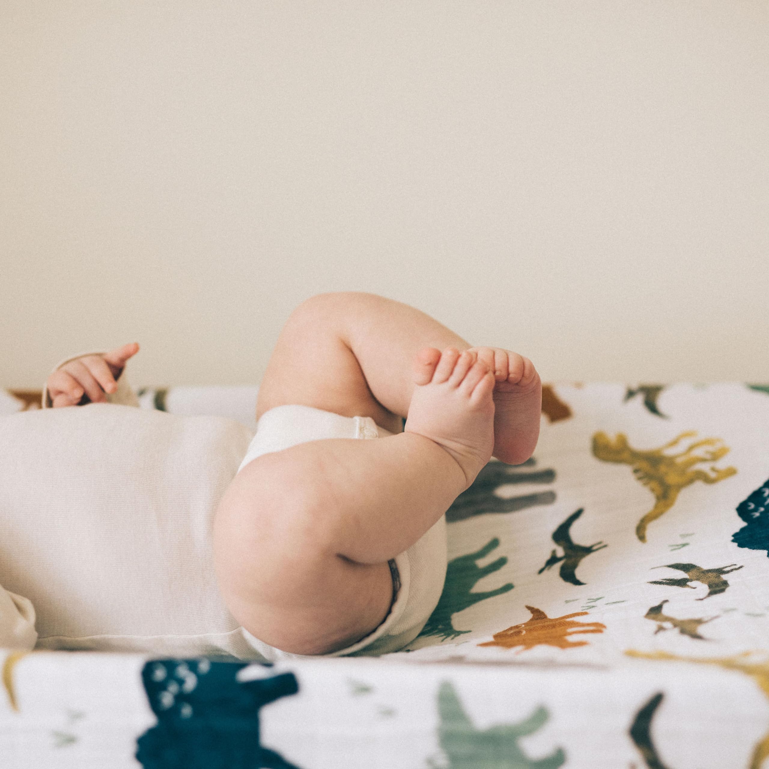 Little Unicorn Dino Friends changing pad cover elastic edge for secure fit during changes.