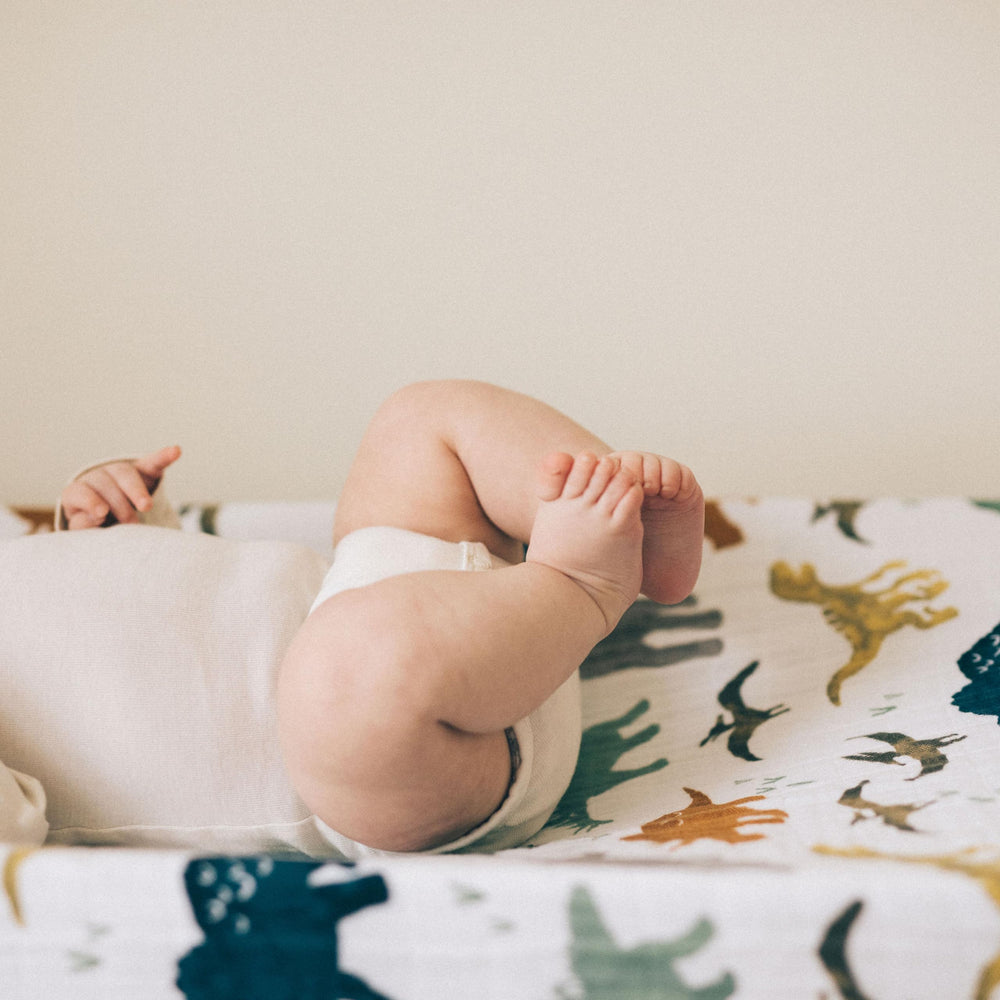 Little Unicorn Dino Friends changing pad cover elastic edge for secure fit during changes.