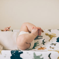 Little Unicorn Dino Friends changing pad cover elastic edge for secure fit during changes.