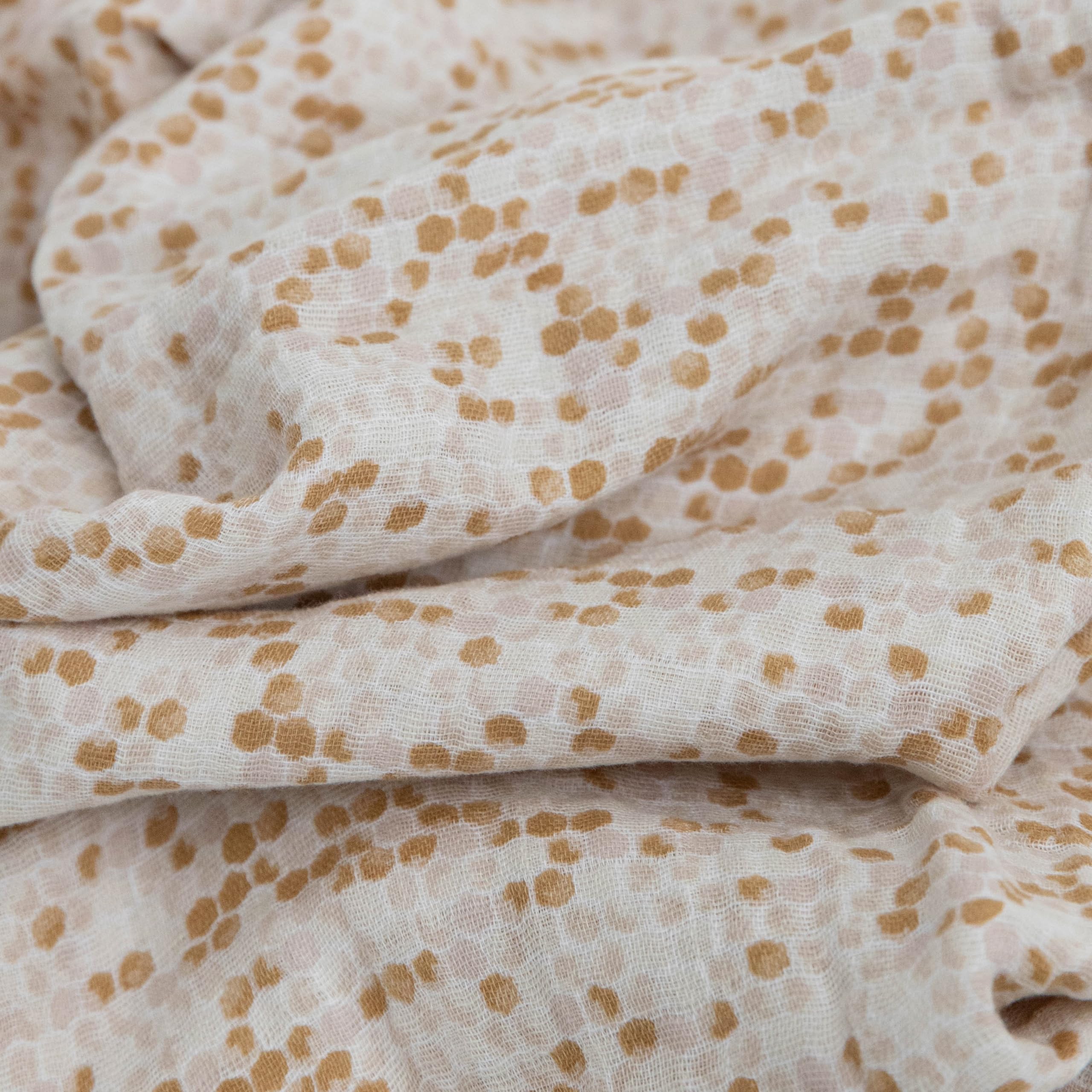 Little Unicorn Garden Bees swaddle on baby – secure wrap encouraging calm sleep.