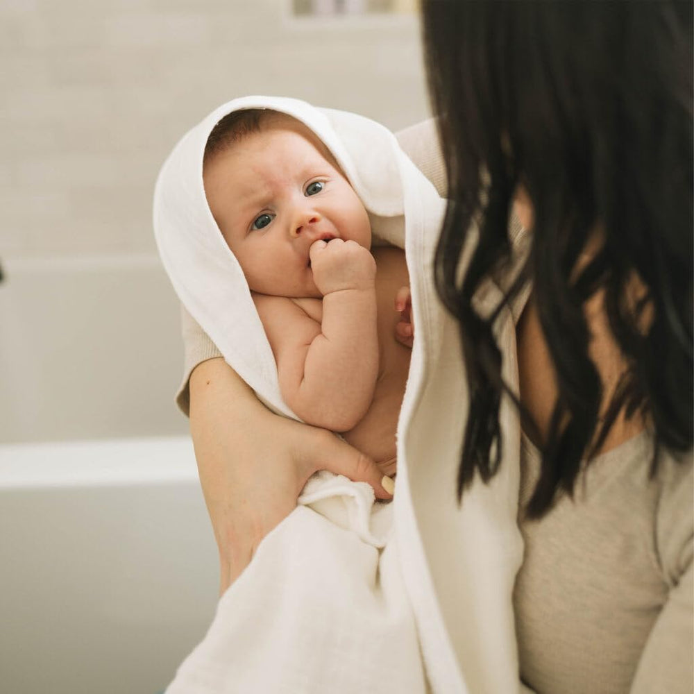 Baby wrapped in Little Unicorn hooded towel for cozy post-bath moment