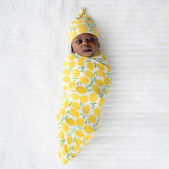 Little Sleepies lemon swaddle set on bed shows versatile, comfy sleep and travel essential.
