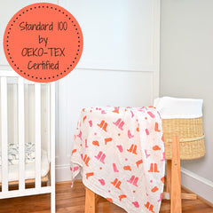 LollyBanks pink boot print swaddle shown as nursery decor-friendly and baby-friendly.