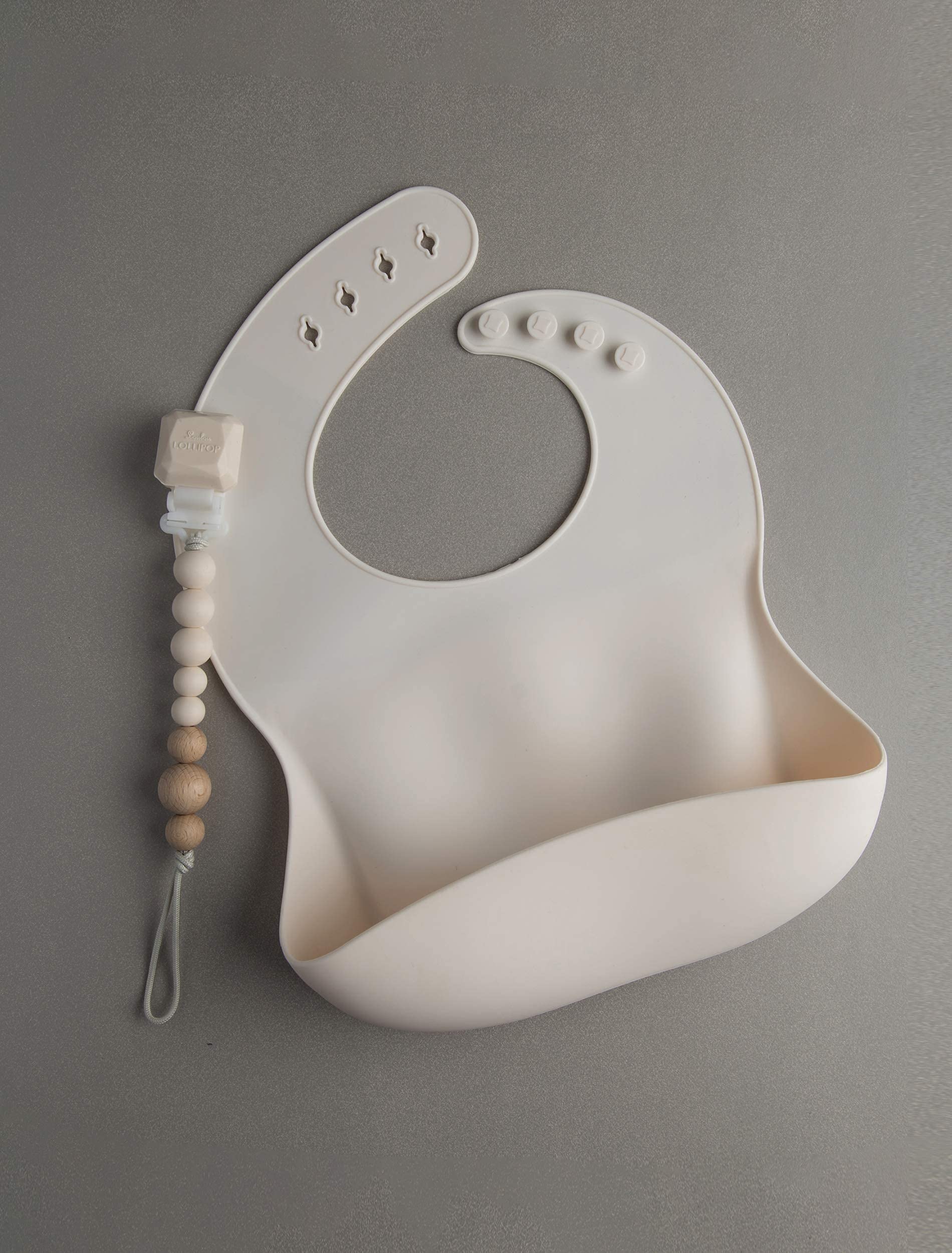 Loulou Lollipop bib Coconut Cream being cleaned under running water.
