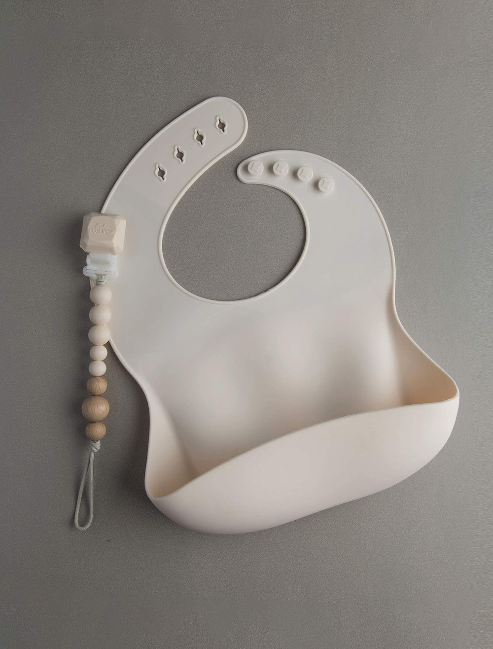 Loulou Lollipop bib Coconut Cream being cleaned under running water.