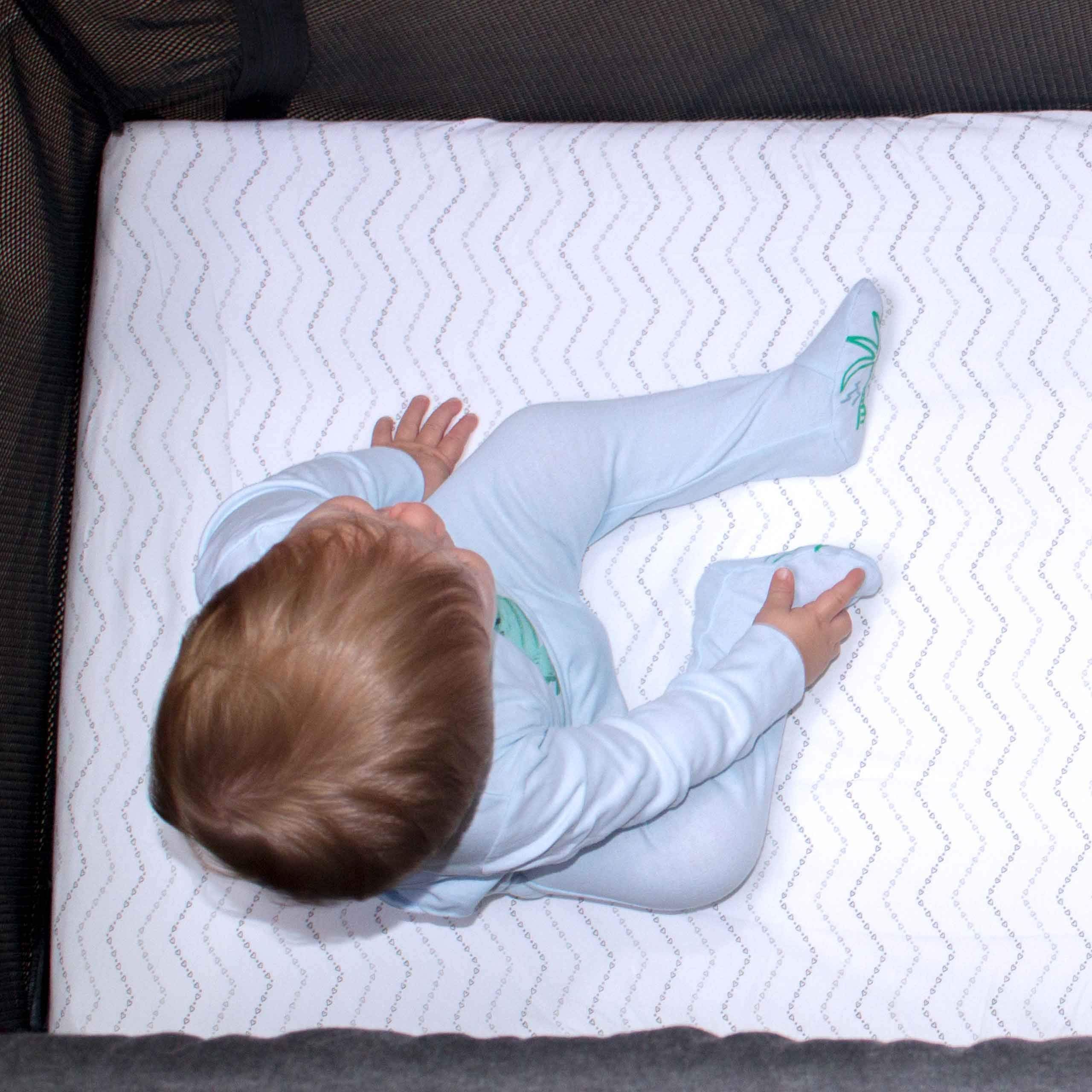 Luvberries Guava Lotus sheets on mini crib—snug fit with secure elastic.