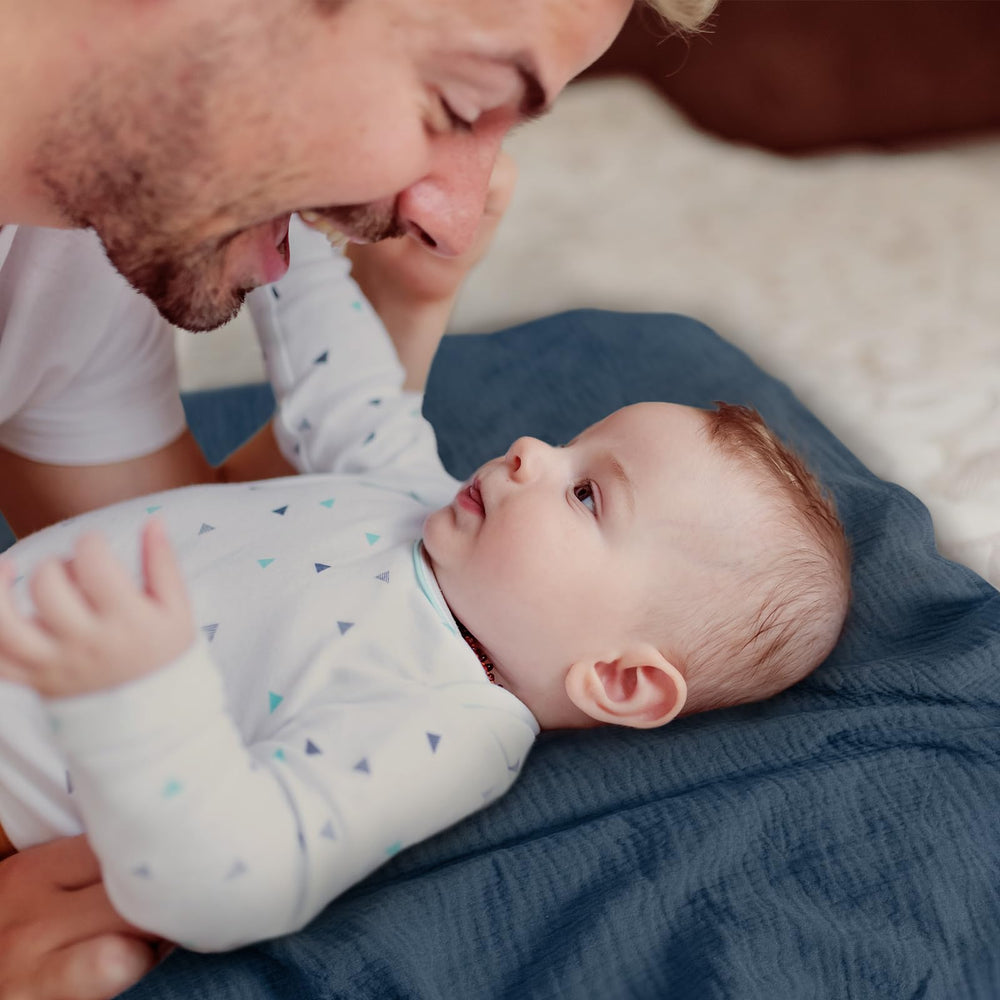 LYRICHOM BABY muslin swaddle blanket cradles baby snugly, suggesting cozy nighttime use.