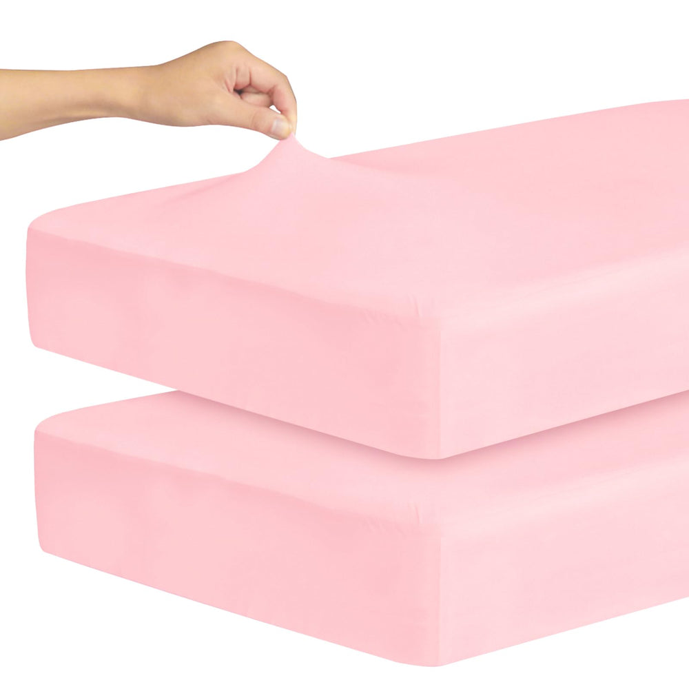 Magik & Kover pink stretchy crib sheet folded, showcasing soft microfiber comfort for baby sleep.