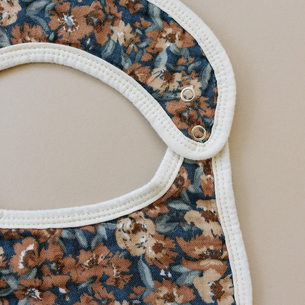 Mebie Baby muslin bib fastened on baby, showcasing easy on and off design