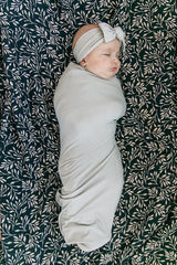 Mebie Baby Stone Swaddle in a nursery scene shows versatile styling options.