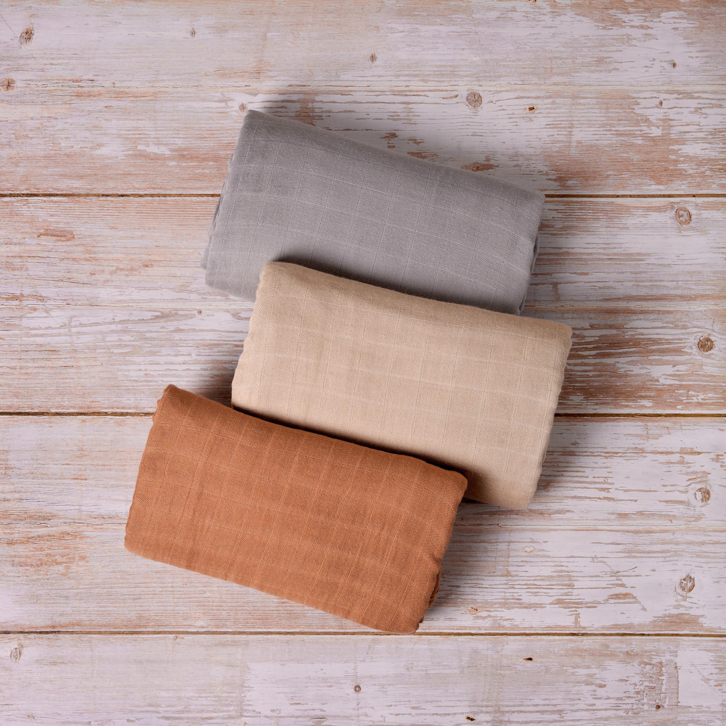 Meracorallo camel muslin swaddle blanket gently wrapped around a baby