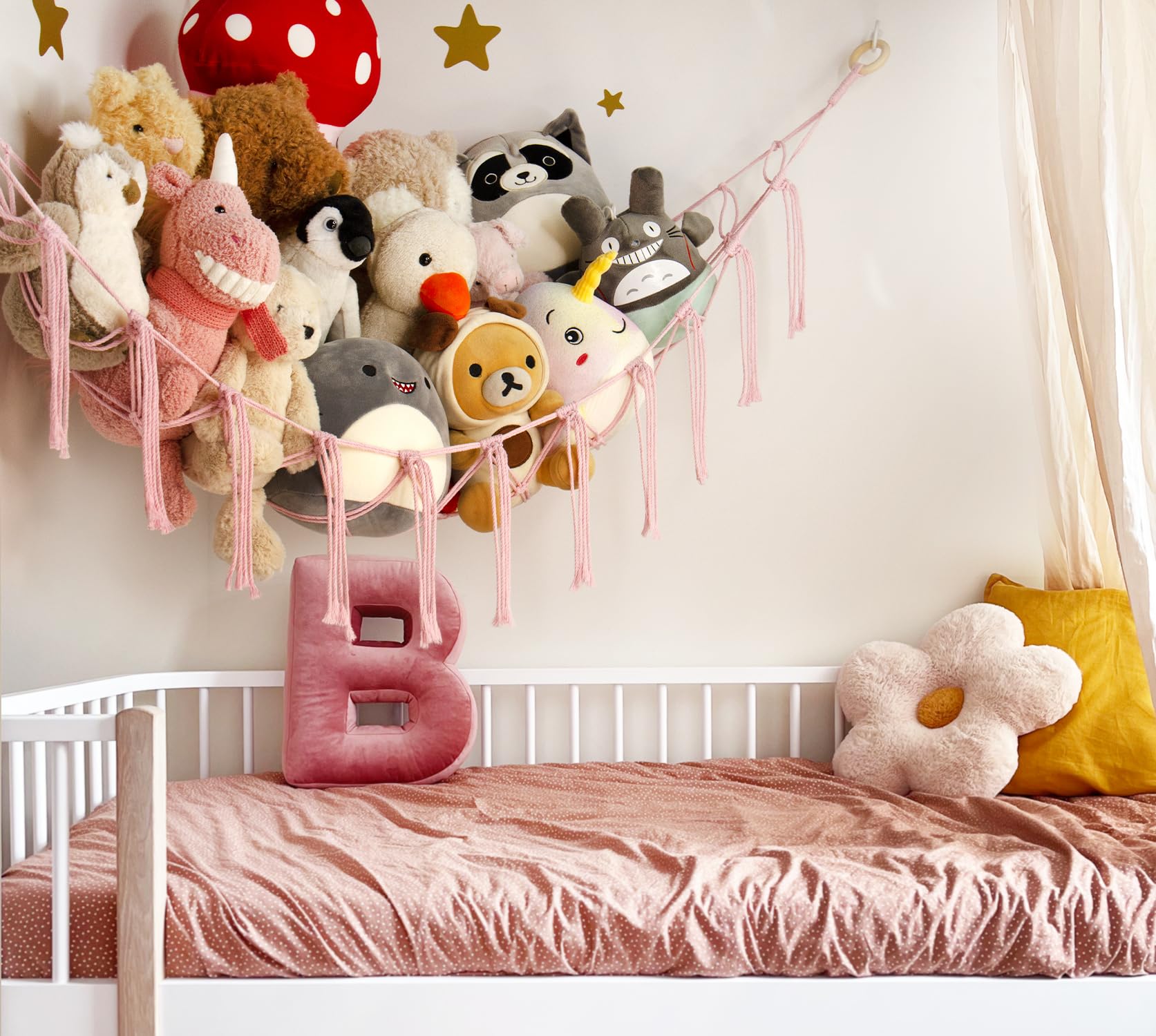 Mirolam boho toy hammock on wall displaying toys in pink decor.