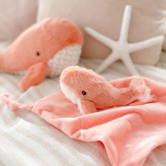 MON AMI Coral Whale Lovey baby grasping a plush whale body for soft sensory play.