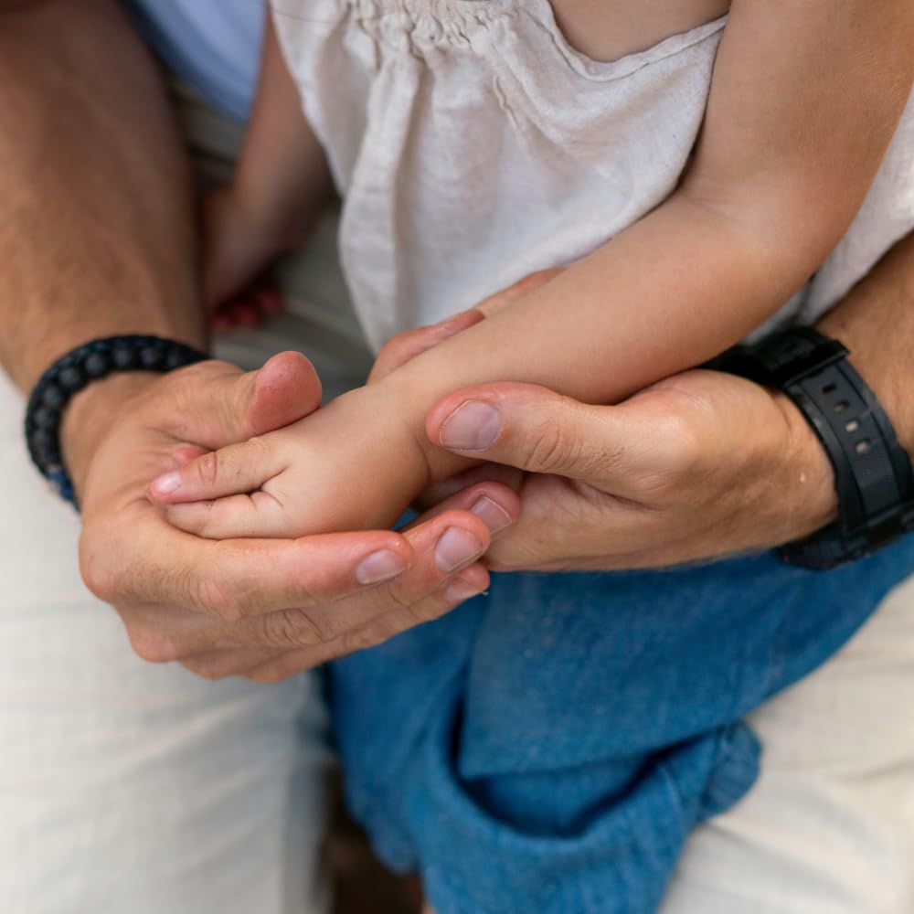 Daily-use image of caregiver applying balm to baby's cheeks for daily comfort.