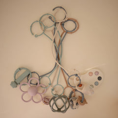Mushie adjustable silicone toy straps holding a sippy cup for quick access.