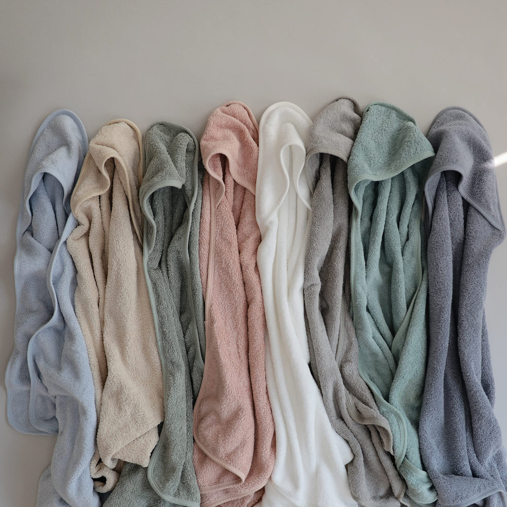 Mushie hooded towel pearl unfolded on surface to reveal generous size and absorbent fabric.