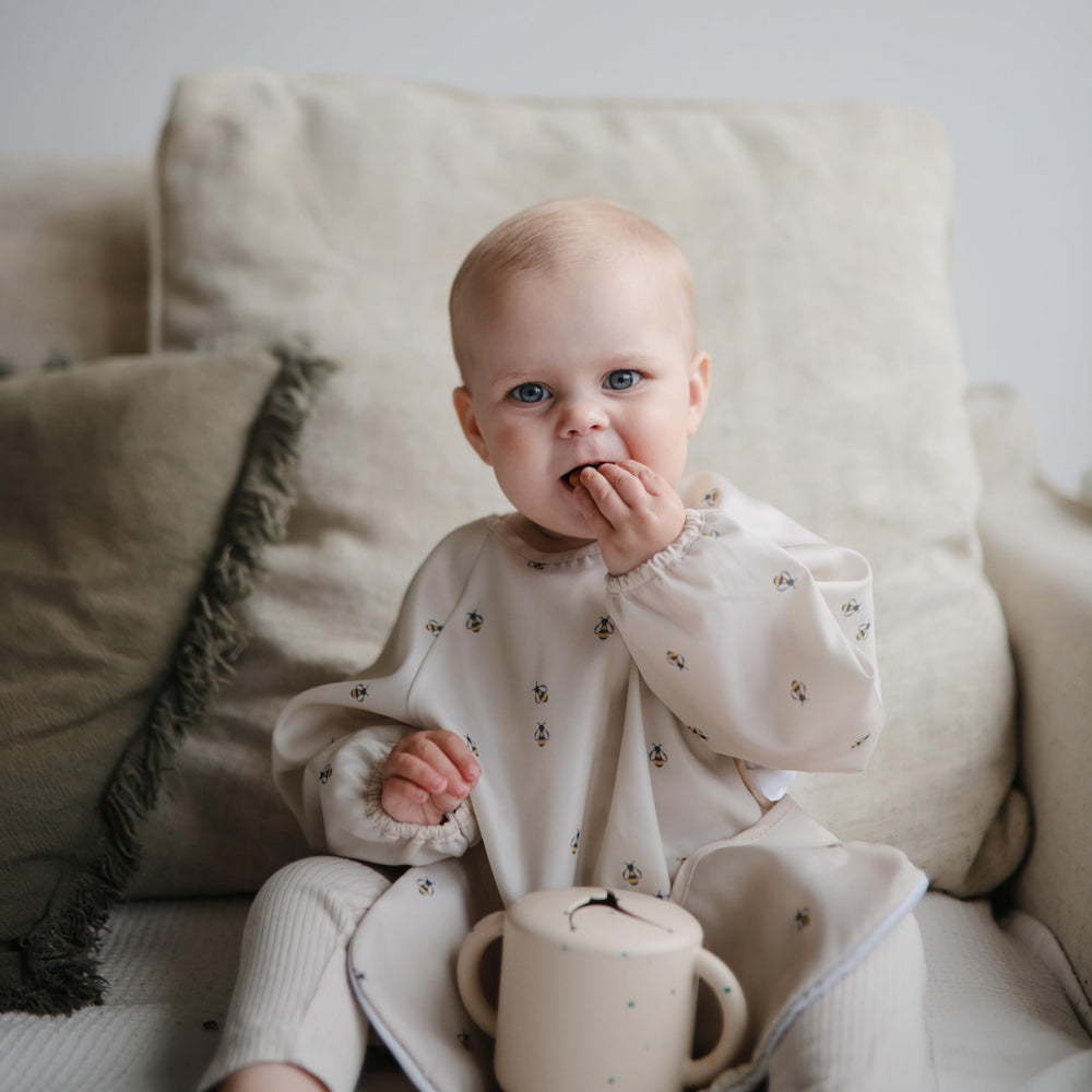 Mushie Bees long sleeve bib neck closure detail demonstrates secure adjustable fit.