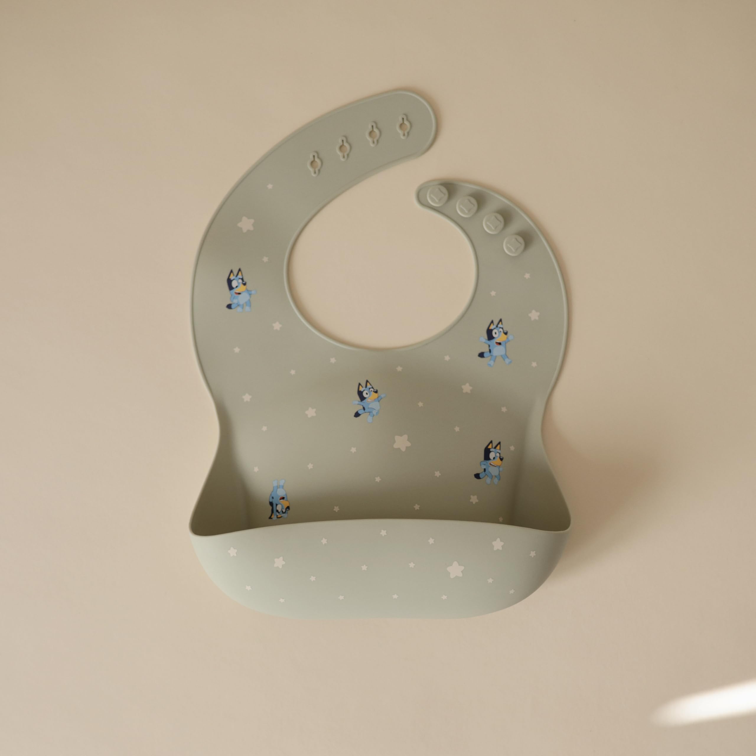 Mushie Bluey bib showing adjustable closure that grows with baby