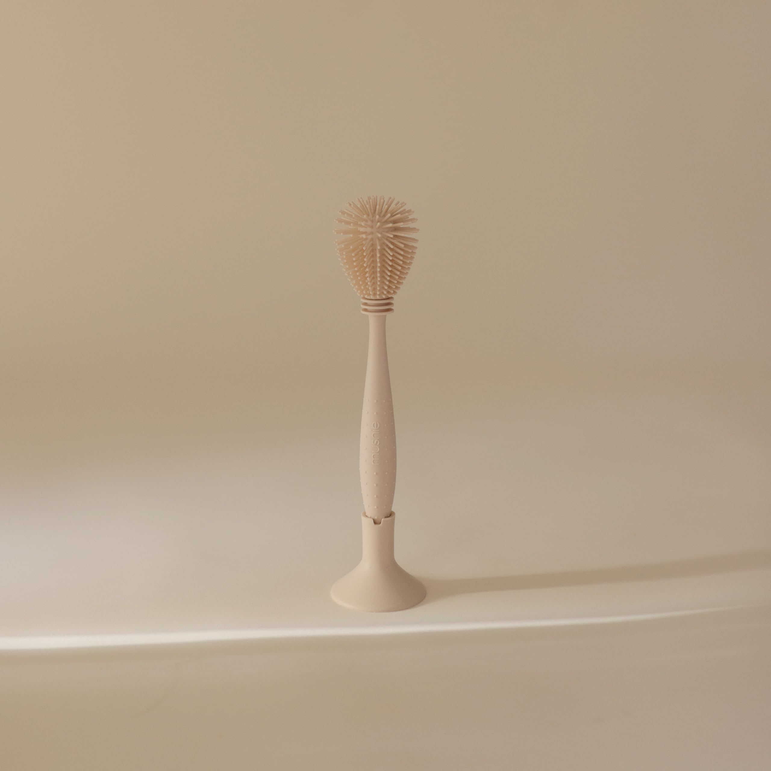 Mushie bottle brush suction base storage keeps counter tidy.