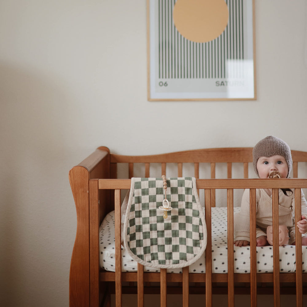 Mushie muslin baby burp cloth set on changing pad for soft, absorbent protection.