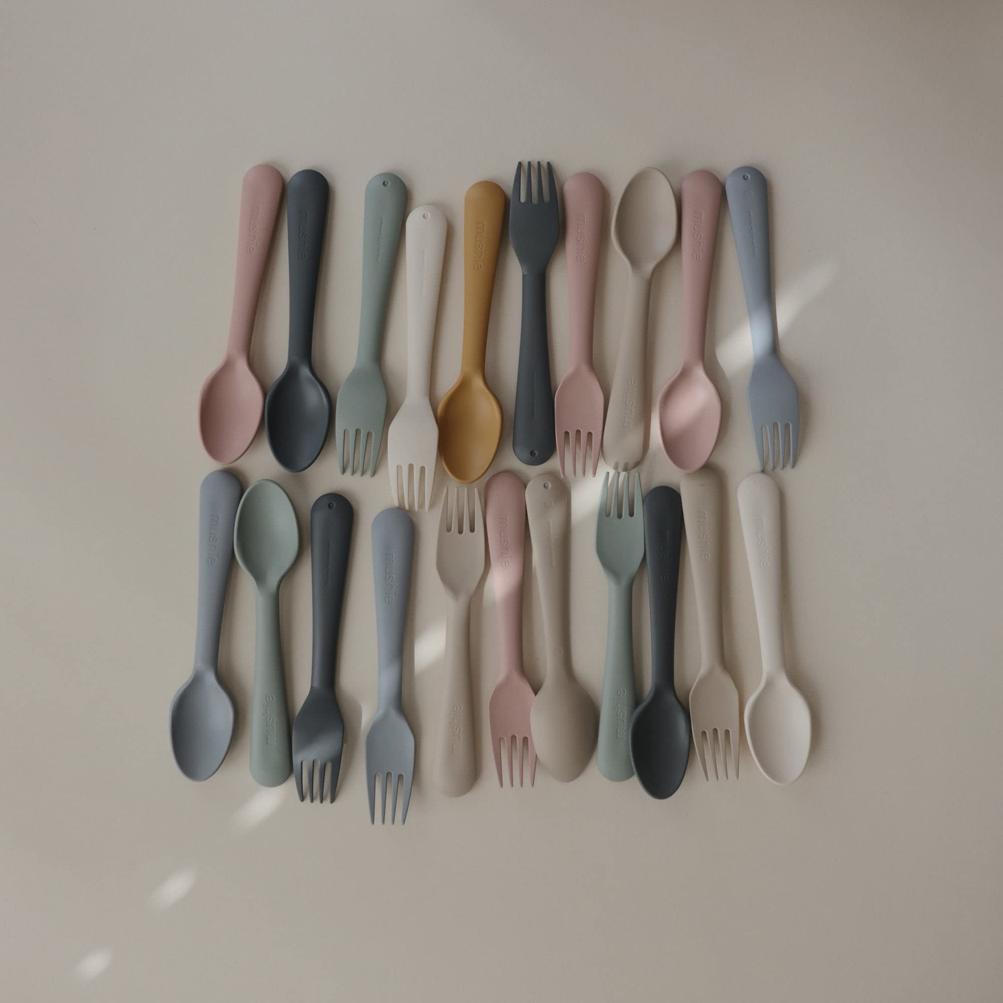 Mushie child mealtime setup with flatware aiding independent feeding
