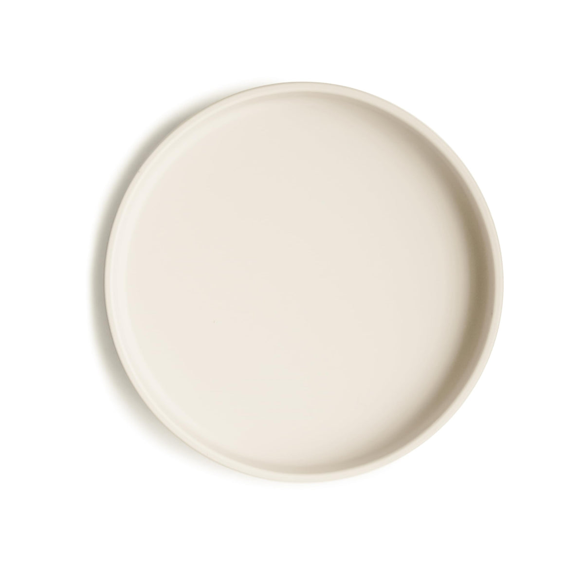 Mushie classic silicone suction plate ivory on table shows secure grip for mess-free meals.