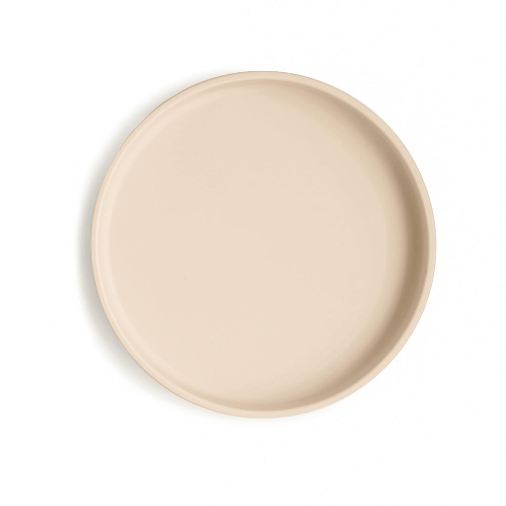 Mushie Classic Silicone Suction Plate on table in shifting sand color, reducing spills during meals