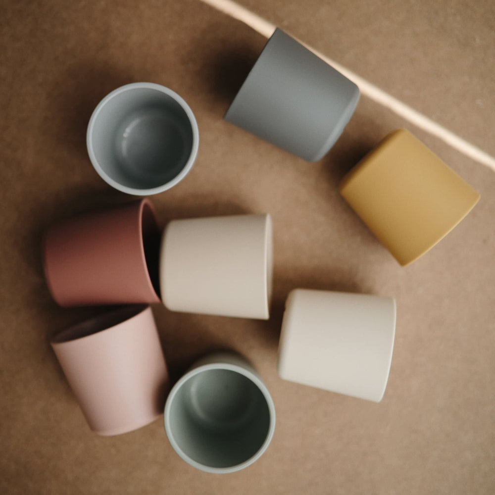 Mushie Sage cups in soft color brighten family mealtimes.