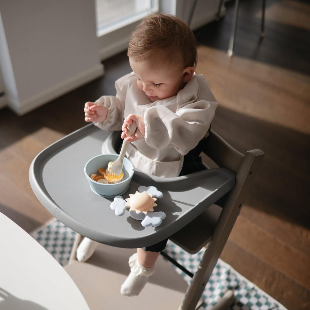 Mushie fork sage held by kid highlights kid-friendly size and control.