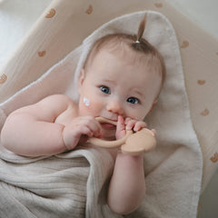 Mushie Dog Brown Teether in hand demonstrates ergonomic grip for tiny hands
