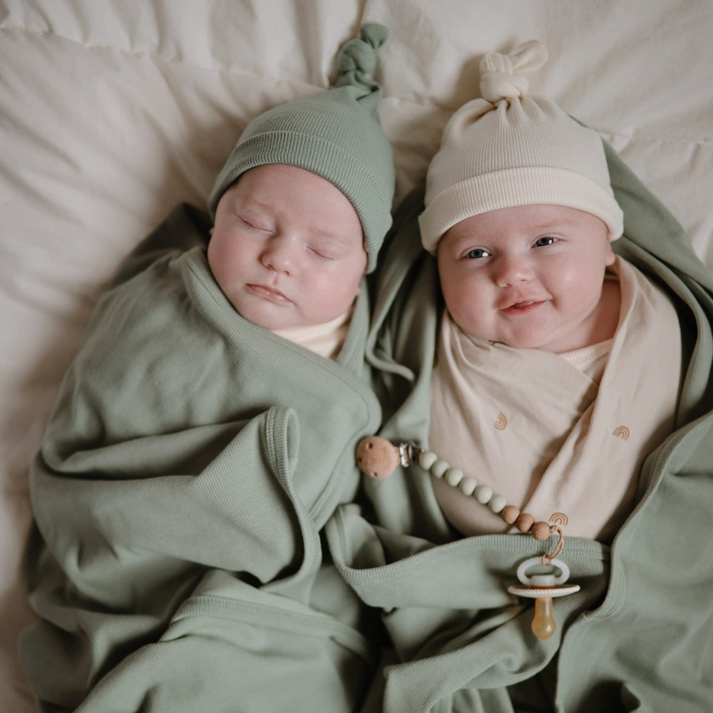 Mushie ribbed blanket in Roman Green draped over baby for nap time comfort