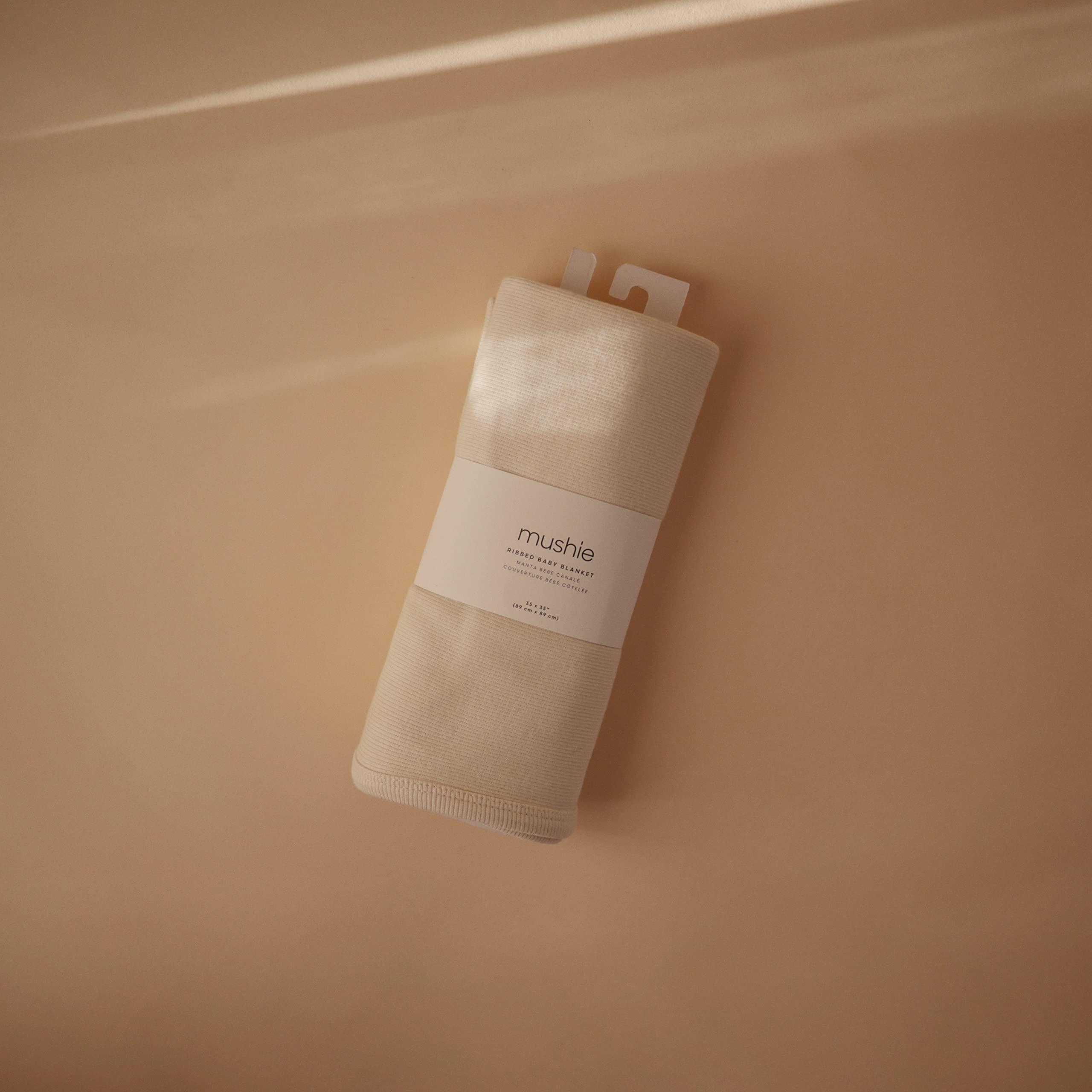 Mushie ribbed blanket Ivory swaddle setup highlighting easy wrapping and secure comfort.