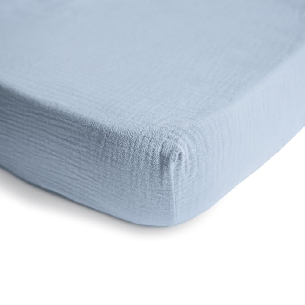 Mushie extra-soft muslin crib sheet baby blue on mattress with snug fit demonstration.