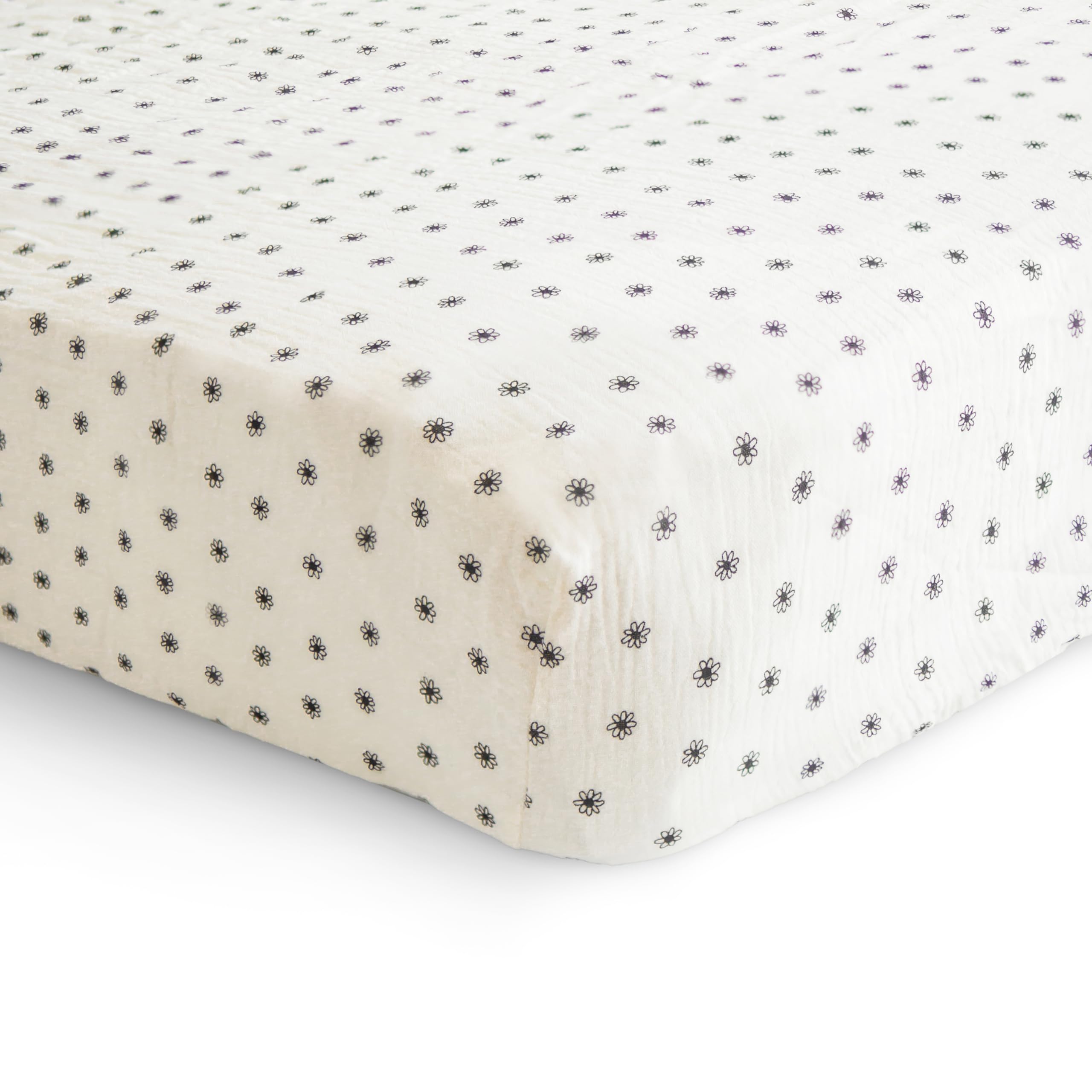 Mushie crib sheet on mattress demonstrates snug fit with deep pockets.