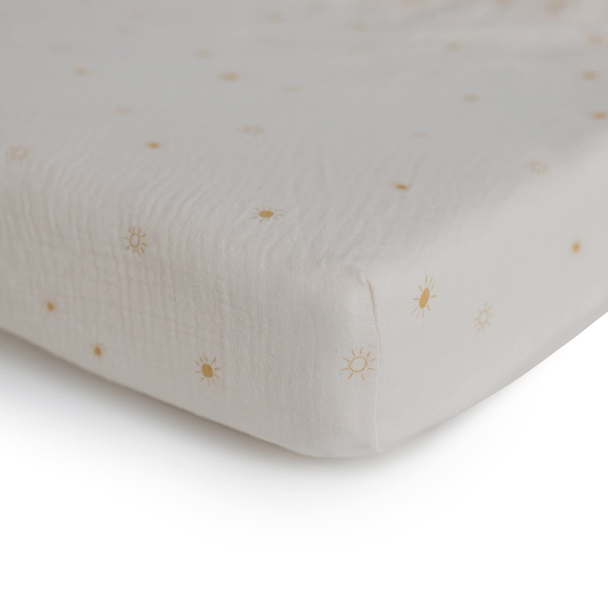 Mushie sun mini crib sheet on mattress shows snug elastic edges for easy nightly changes