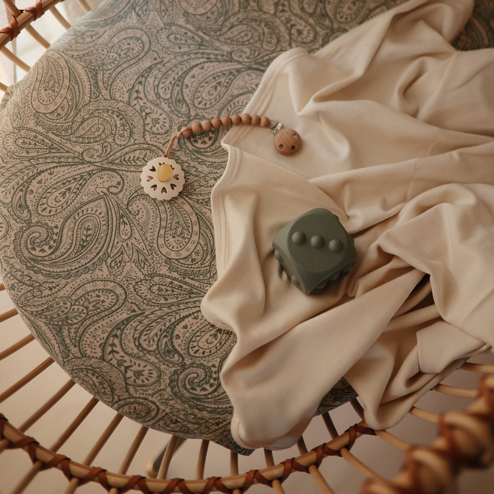 Mushie green paisley design crib sheet emphasizes calming nursery aesthetics.