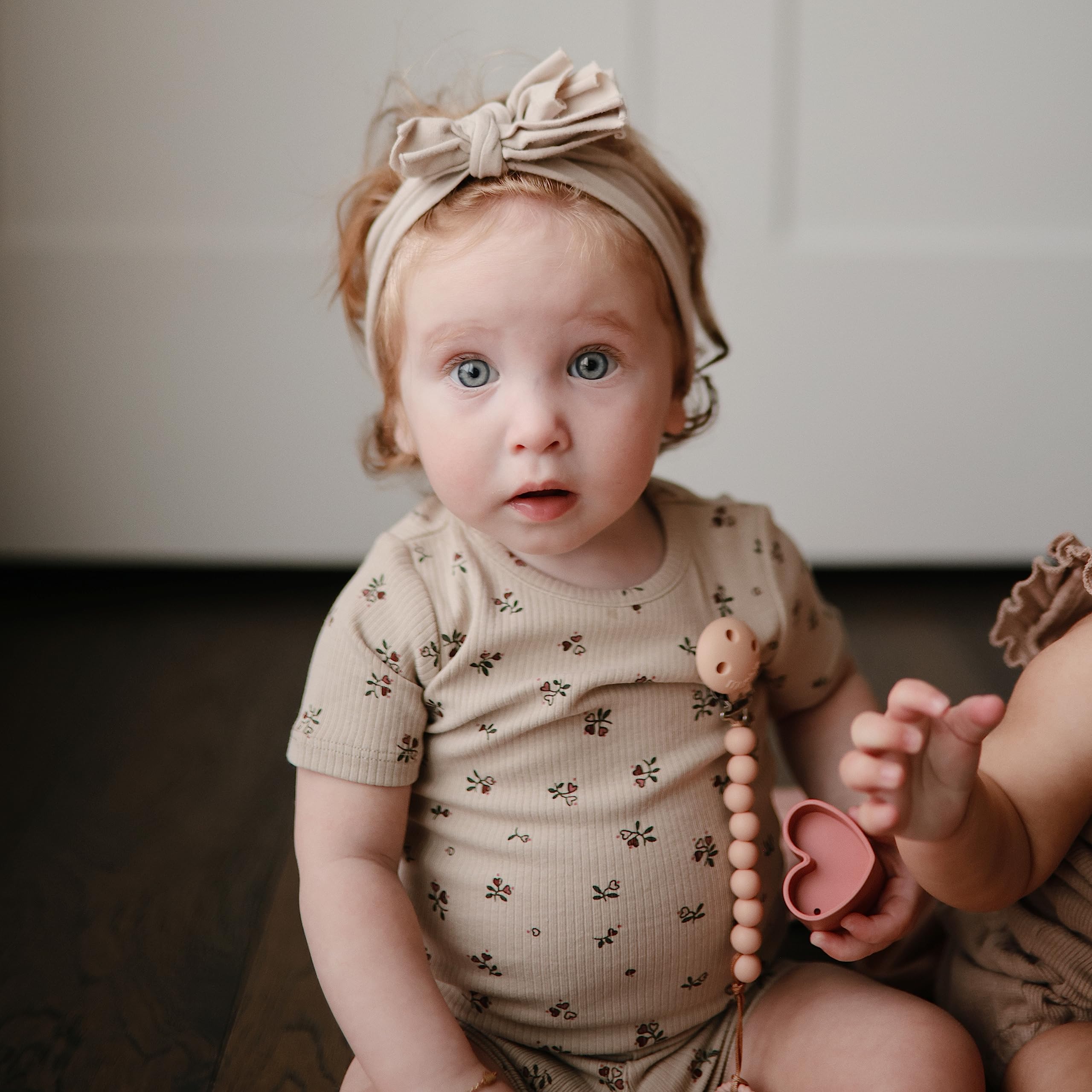 Mushie Hera pacifier clip in soft color palette complements outfits.