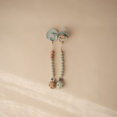 Mushie Hera Sage pacifier clip beads stack highlights soft calming colors.