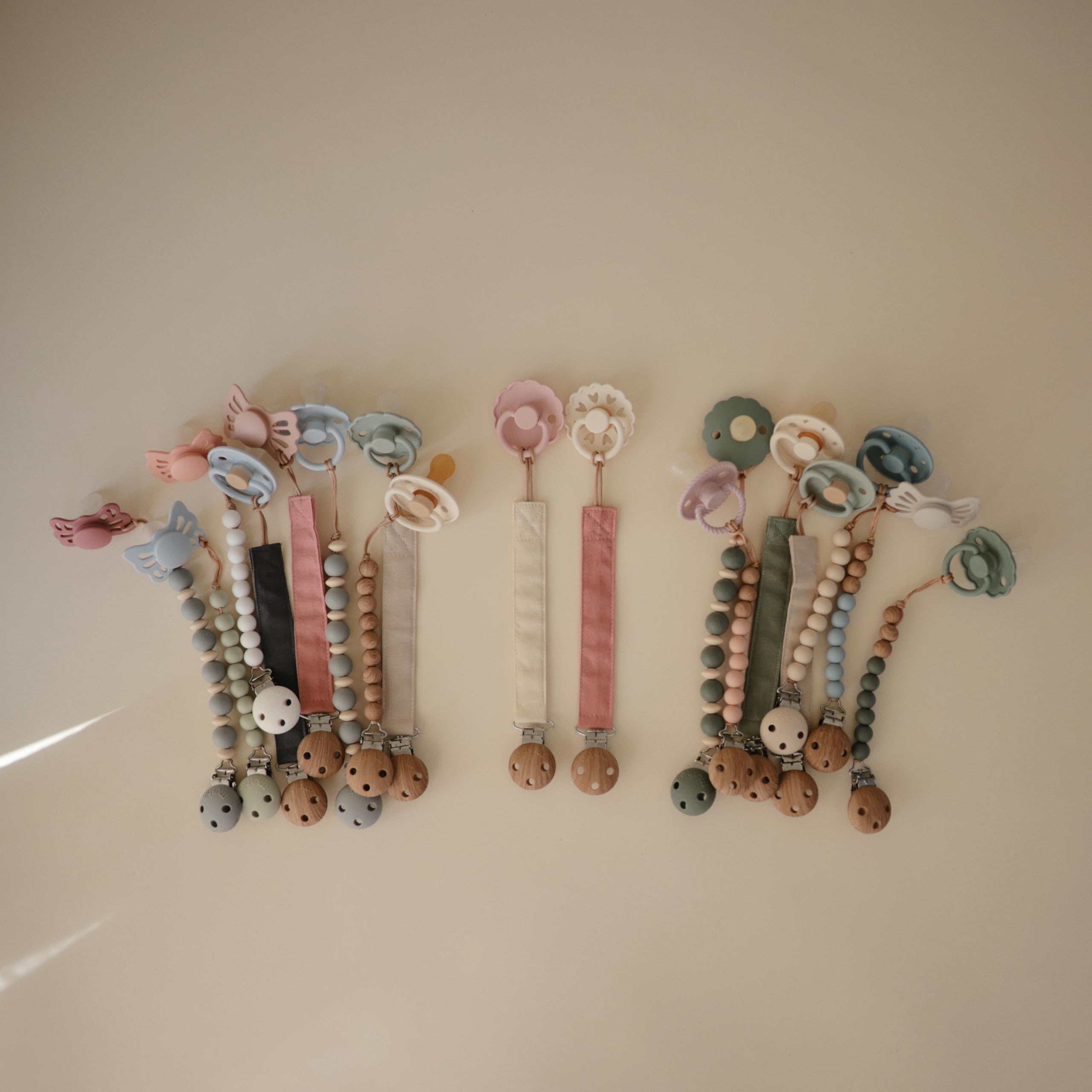 Mushie linen pacifier clip Dusty Rose with faux wood clasp for secure pacifier hold.