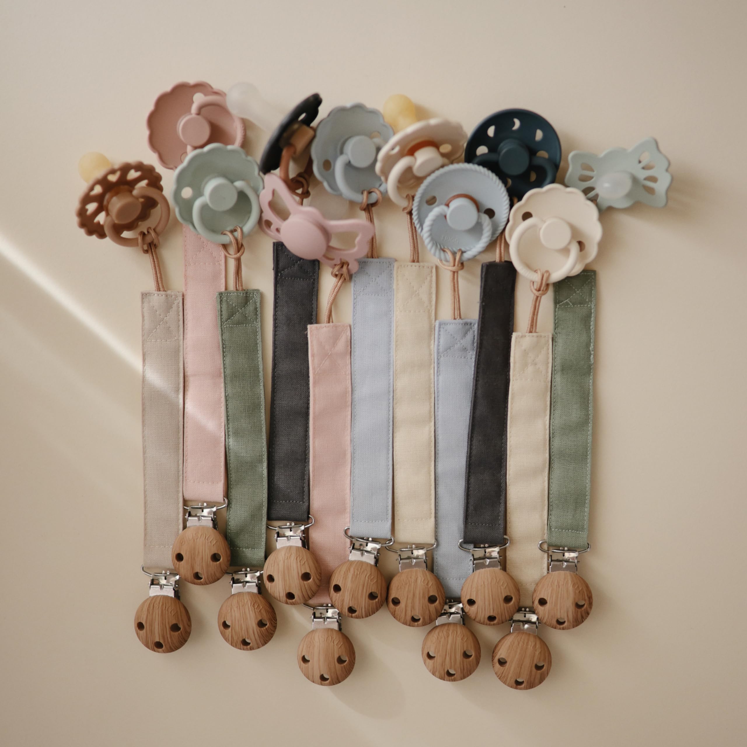 Mushie linen pacifier clip shifting-sand closeup highlights soft fabric and secure clasp for mess-free use