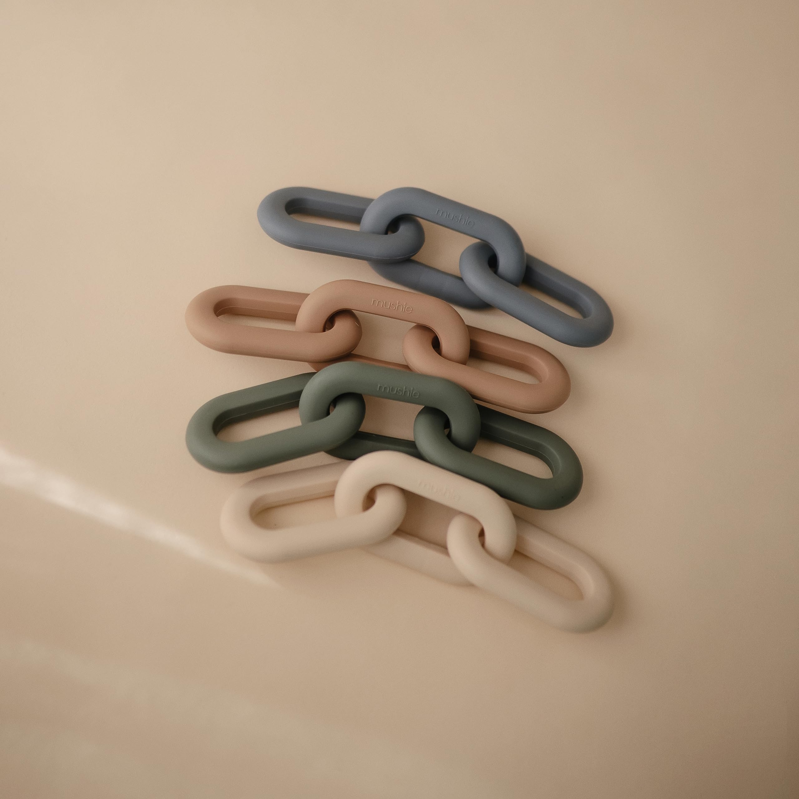 Mushie Links Teether in hand showcases portable comfort for on-the-go soothing.
