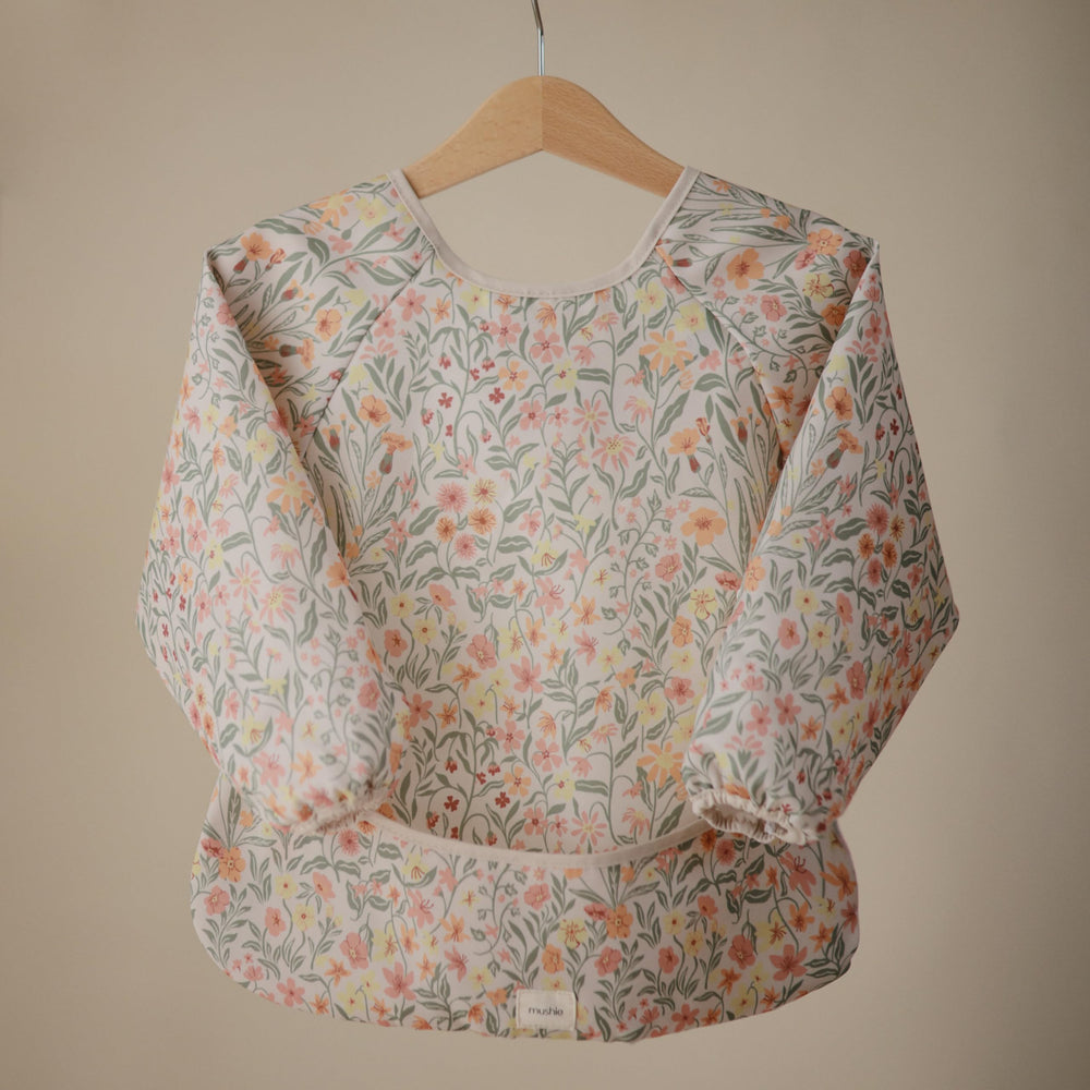 Mushie Long Sleeve Bib Pastel Blooms during mealtime catching crumbs and protecting outfits.