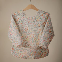 Mushie Long Sleeve Bib Pastel Blooms during mealtime catching crumbs and protecting outfits.