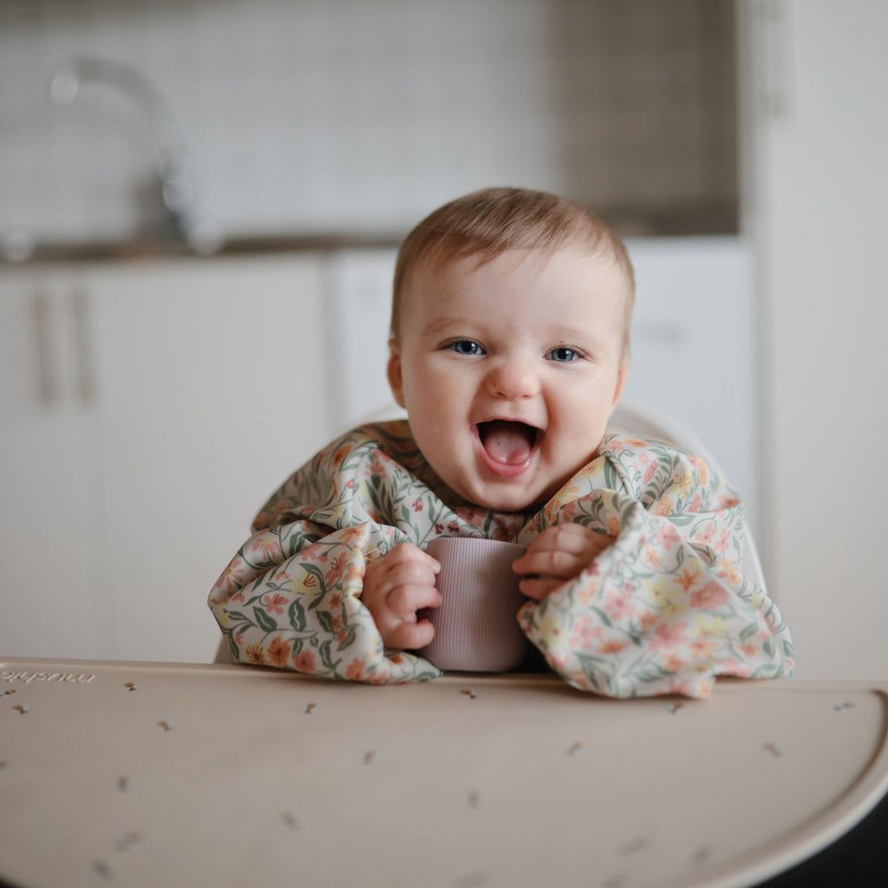 Mushie Long Sleeve Bib Pastel Blooms sized for 6-24 months wearers.