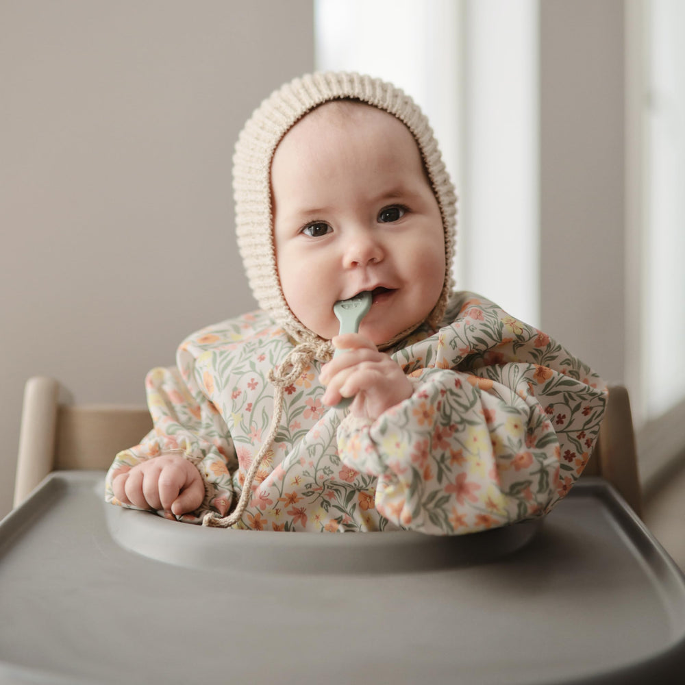 Mushie Long Sleeve Bib Pastel Blooms wipe-clean fabric, machine washable for busy days.