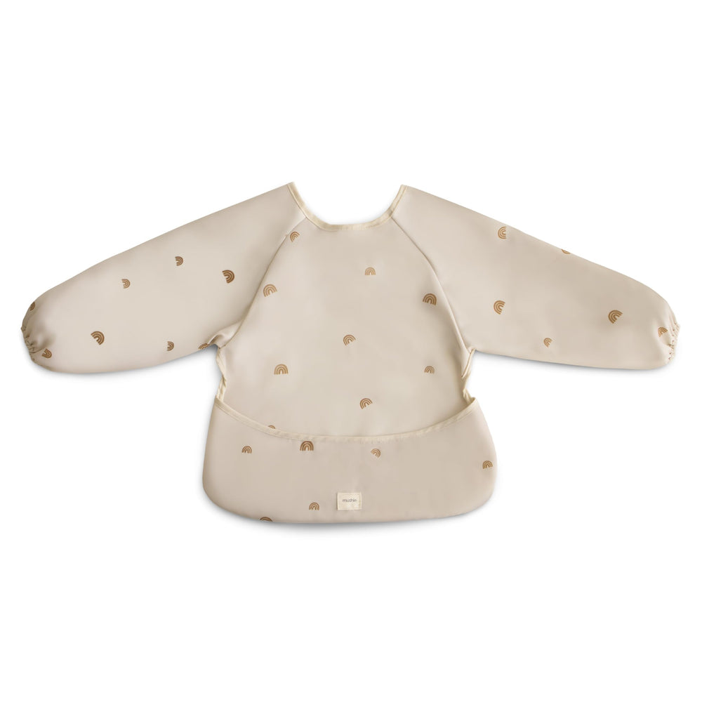 Mushie long sleeve bib Rainbows worn by baby showing full coverage during meals.